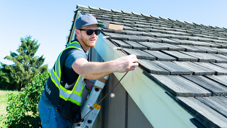 Professional Christmas light installer stringing up lights on a roof