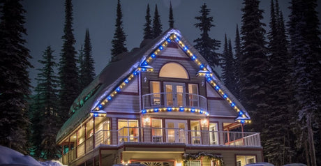 Lit home in winter wonderland with forest in the background